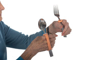 Woman with stroke grasps eating utensils with an inexpensive orange silicone eating aid