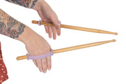 Adult with grip disability using drumsticks modified with an assistive device to aid in grasp.