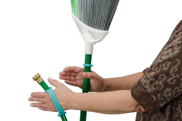 Person with disability holds a hose and broom with an Aqua eazyhold and 