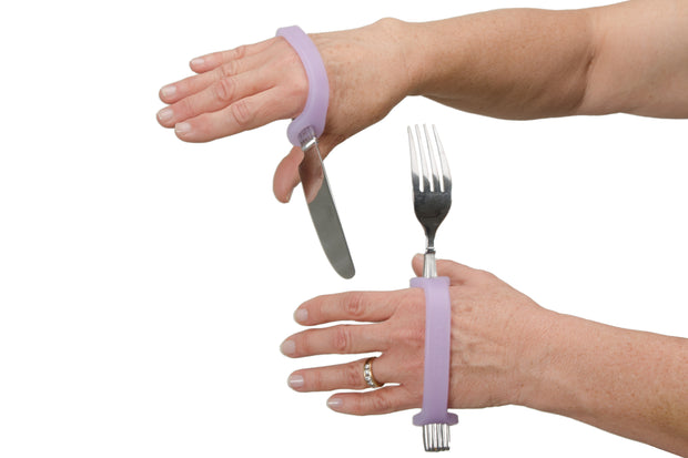 Two hands with cerebral palsy hold a fork and knife with lavender eazyhold's on the handles.