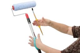 Person with reduced grip holding a paint brush and roller with aqua eazyhold universal cuffs