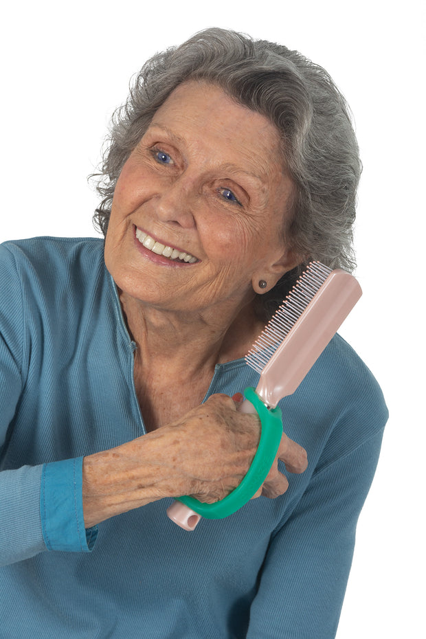 Disabled woman gripping a hairbrush with the help of a grooming aid 