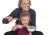 Mom with arthritis and child with autism hold spoons using the eazyhold eating aids.