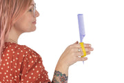 Women with grip issues hold a comb with a yellow silicone eazyhold on her 3 fingers.